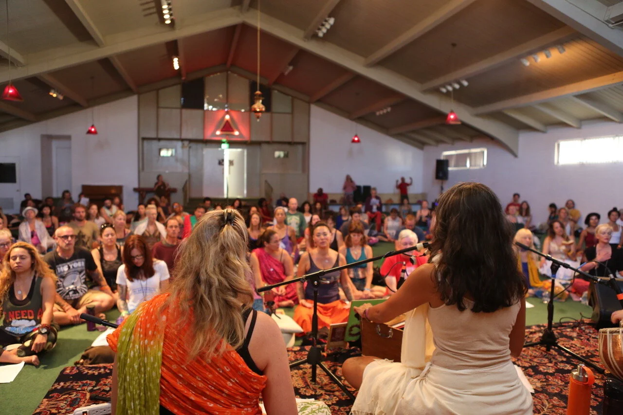 A room full of people gathered in communal kirtan